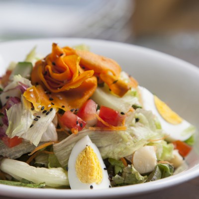Salada Frutaria: Mix de folhas, cenoura ralada, cubos de tomate, palmito, ovo caipira ao molho de mostarda e mix de gergelim. 